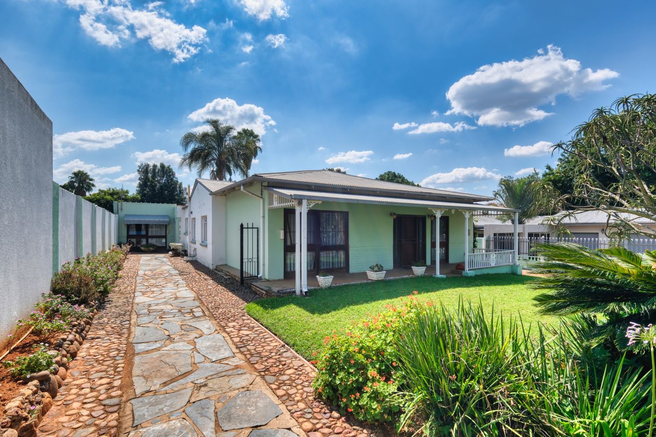 Picture of a charming residential house with vibrant garden under a sunny sky.